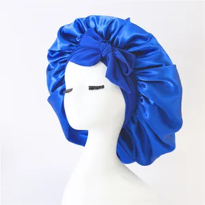 Detail of bright blue satin bonnet with large bow on white mannequin showing silk texture