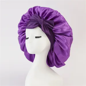 Detail of purple satin sleep bonnet with bow accent on a model head stand