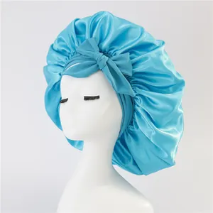 Detail of teal satin hair bonnet featuring a large decorative bow on a mannequin head