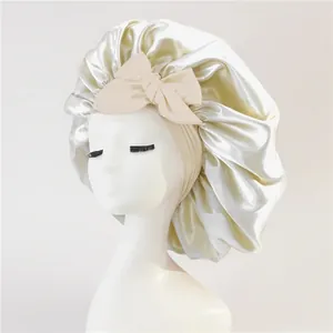 Detail of champagne satin bonnet featuring a large decorative bow and elastic wide band