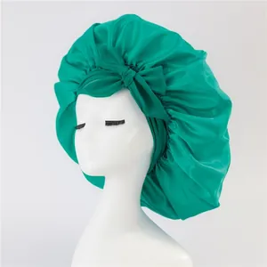 Detail of emerald green satin bonnet with a large decorative bow on a white mannequin head