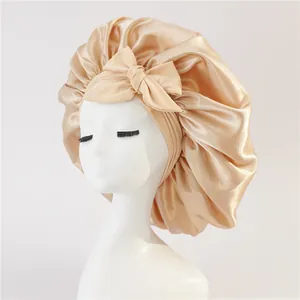 Close-up of champagne gold satin bonnet with large bow detail on a white mannequin head