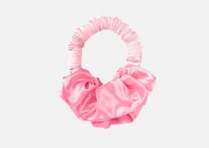 Gros plan d'un bigoudi en satin rose montrant la texture de soie et les froufrous doux