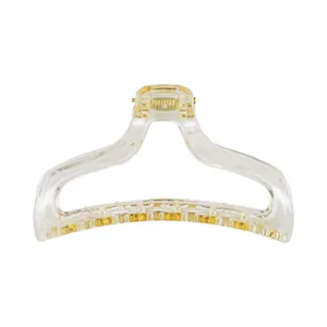 Macro detail of transparent hair claw clip showing gold metal spring and teeth