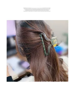 Transparent green shark hair claw clip holding long brown hair in a stylish bun