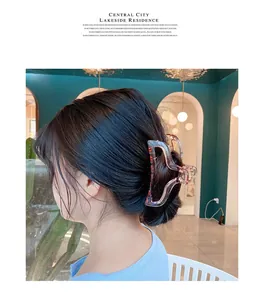 Close-up of a translucent pink wave-shaped shark clip styling a bun on a female model