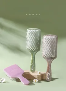 Detail view of square paddle hairbrushes with elegant totem patterns in pastel colors