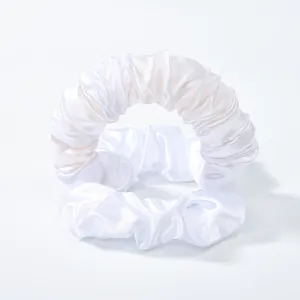 Dettaglio di due elastici scrunchie in raso bianco dalla trama setosa e lucentezza