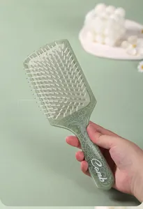 Detail of light green square paddle brush with white floral handle and round tip bristles