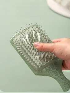 Detail showing the elastic air cushion and rounded massage bristles of the green hairbrush
