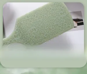 Macro detail of vintage floral pattern on green cushioned hairbrush with lace textures