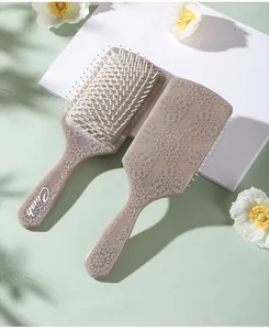 Detail of square cushion hairbrush showing retro damask pattern and ergonomic handle