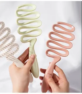 Dettaglio di spazzole per capelli curve e traforate in verde, rosa e beige per massaggio cranico