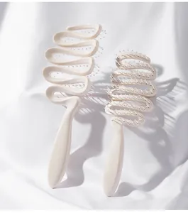Dettaglio delle spazzole per capelli a forma di S color crema su seta bianca