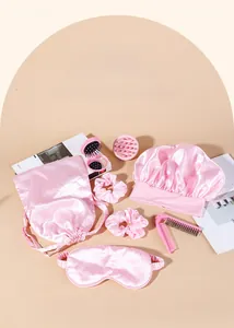 Pink satin hair care set including sleep mask, hair cap, massage brush, and folding comb