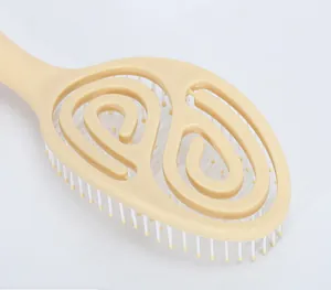 Detail of hollow spiral hair brush with yellow rounded massage bristles on white background