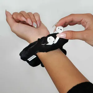 Detail of black velvet zipper scrunchie with hidden pocket holding wireless earbuds