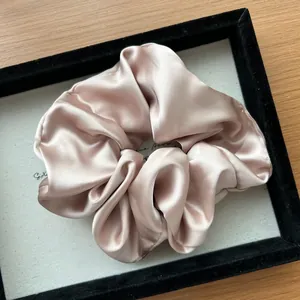 Dettaglio dell'elastico in raso champagne con pieghe setose in un vassoio elegante