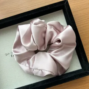 Dettaglio di un elastico per capelli in raso di seta rosa con elegante trama plissettata