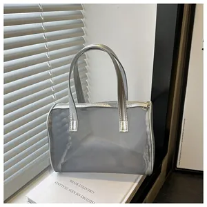 Gedetailleerde close-up van een zilveren mesh shopper met metallic leren bies en rits