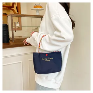 Dettaglio della borsa tote blu scuro con stampa dorata e manici colorati intrecciati