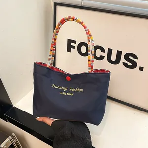 Borsa tote retrò blu navy con stampa a lettere dorate e manici intrecciati colorati