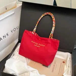 Borsa tote in tela rossa con manici intrecciati colorati e logo dorato ricamato
