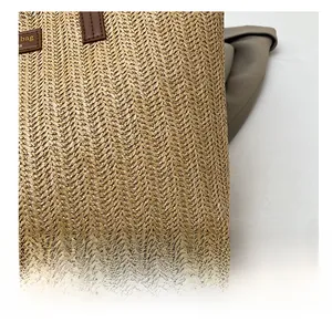 Vue détaillée du tissage en paille kaki et de l'empiècement en cuir marron sur le sac
