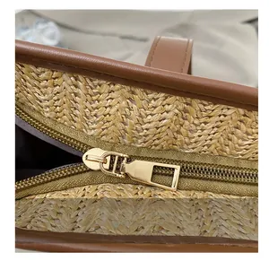 Détail de la fermeture éclair en métal et garniture en cuir brun sur le sac en paille