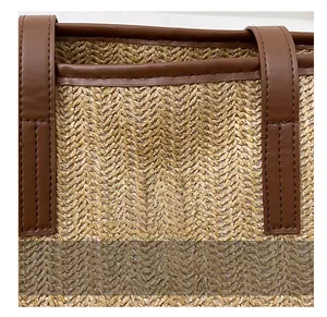 Détail macro du sac cabas en paille tissée avec garniture en similicuir marron et logo