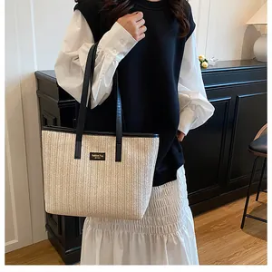 Détail du sac cabas en paille à chevrons avec bordures en cuir noir et logo mode