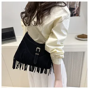 Detalle del bolso de hombro negro con flecos, textura mate y hebilla de metal
