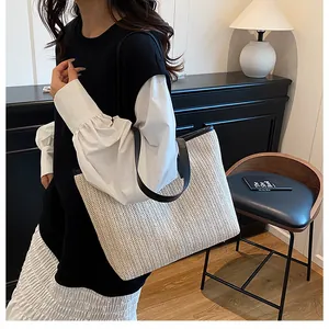 Gros plan du grand sac cabas en paille avec anses en cuir noir et design épuré