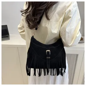 Detalle de bolso bandolera con flecos negros en ante con hebilla y herrajes plateados