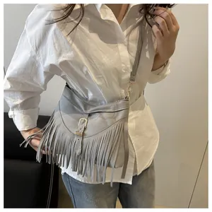 Detalle del bolso bandolera de flecos gris claro con textura de ante y hebilla dorada