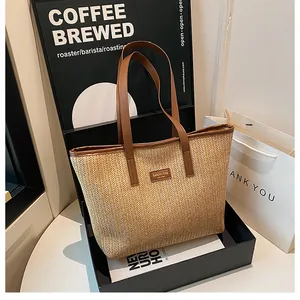 Détail d'un sac cabas en paille tissée à chevrons avec lanières en cuir et étiquette