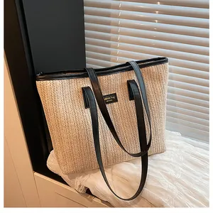 Détail du sac cabas en paille avec anses en cuir noir et étiquette sur un rebord