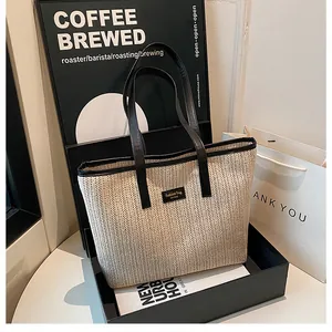 Gros plan sur un sac cabas en paille beige avec poignées et empiècement en cuir noir