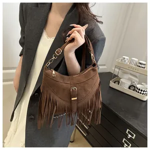 Detalle de bolso bandolera de ante marrón oscuro con flecos y cadena en tono dorado