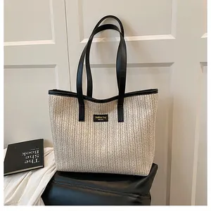 Vue détaillée du grand sac cabas en paille tissée avec anses en cuir noir