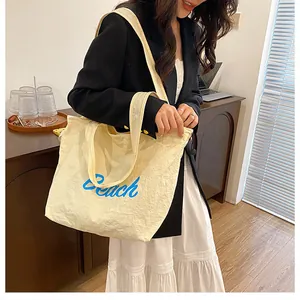 Détail d'un grand sac fourre-tout en toile crème avec texte Beach bleu en intérieur