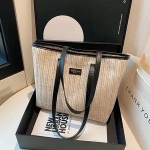 Grand sac cabas en paille avec lanières en cuir noir et étiquette de mode en studio