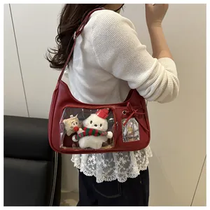 Detail view of burgundy leather ita bag with clear windows displaying plush doll charms