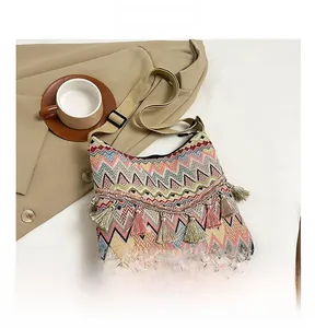 Detail view of woven shoulder bag with vibrant zig-zag patterns and decorative tassels