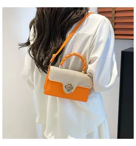 Détail du fermoir rotatif en forme de fleur dorée sur le sac à main orange à texture tressée