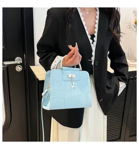 Detail of light blue crocodile texture handbag with gold handle and deer charm