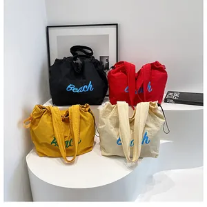 Gros plan de sacs fourre-tout à cordon légers avec lettrage Beach en quatre coloris