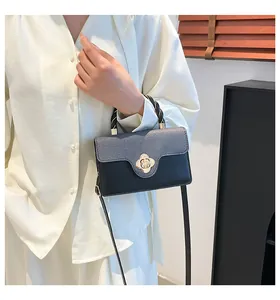 Détail du sac à main bicolore avec fermoir fleur en métal et poignée tissée élégante