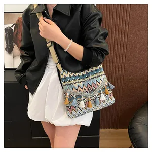 Close-up of ethnic canvas crossbody bag with colorful wave patterns and cotton tassels