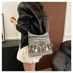 Close-up of bohemian shoulder bag with geometric patterns, metal chains and colorful tassels
